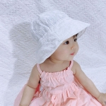 Kleine Asiatin sitzt mit einem rosa Kleid und einer weißen Baskenmütze und schaut nach rechts