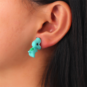 Grüner Ohrring in Form eines Dinosauriers, getragen von einer Frau
