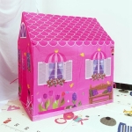 kleines rosafarbenes Mädchenhaus auf einem Teppich mit Mustern
