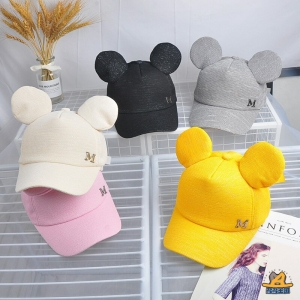 Modische Sommermütze für Kinder in mehreren Farben auf einem Tisch mit einer Vase