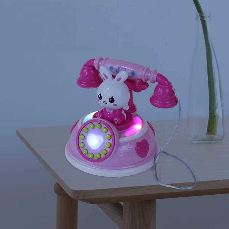 Telefonspielzeug für kleine Mädchen, rosafarben, auf einem Tisch in einem Haus