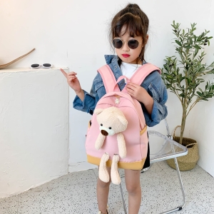 Rucksack mit Teddybär für Mädchen, der von einem Mädchen in einem Haus getragen wird