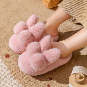 Weiche rosafarbene Plüschpantoffeln in Form eines Hasen, von einem Kind getragen