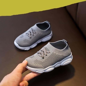 Ein Paar graue, rutschfeste Sneakers in der Hand eines Erwachsenen