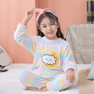 Polarpyjama mit Mond- und Wolkenmotiven für Mädchen, getragen von einem kleinen Mädchen in einem Haus