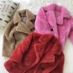 Drei beige, rosa und rote Pelzjacken auf einer weißen Decke