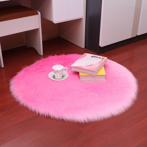 Runder Teppich aus langflorigem Kunstpelz, rosafarben, mit einer Tasse und zwei Büchern darauf