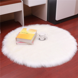 Weißer, runder Teppich aus langhaarigem Kunstpelz auf einem dunklen Parkettboden in einem Schlafzimmer mit einer Tasse und einem Buch darauf