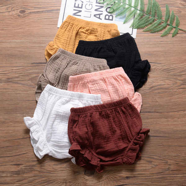 Auf Parkettboden mit grünem Blatt als Dekoration, Babybloomers aus geprägtem und bauschigem Musselin, gelb, schwarz, beige, rosa, weiß und bordeauxrot