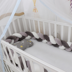 Geflochtene Bettumrandung in grau und weiß für Baby-Mädchen mit einem Hintergrund eine Babywiege mit der Bettumrandung