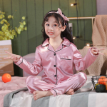 Junges Mädchen im Schneidersitz in rosafarbenem Satinpyjama