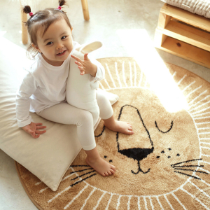 Babyzimmerteppich im nordischen Stil in Form eines Löwen für Mädchen mit einem kleinen Mädchen auf dem Teppich