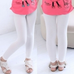 Vorder- und Hinterbein eines kleinen Mädchens, das eine weiße Leggings, ein rosa T-Shirt und Sandalen trägt