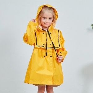 Kleines, lächelndes, blondes Mädchen, stehend, mit gelber Kapuze und Ölzeug