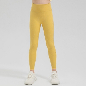 Beine eines stehenden Mädchens in einer glänzenden gelben Sportleggings