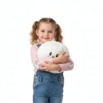 Jeune fille debout avec des couettes, portant un jean et un t-shirt rose, qui tient dans ses bras un squishy dumpling blanc.